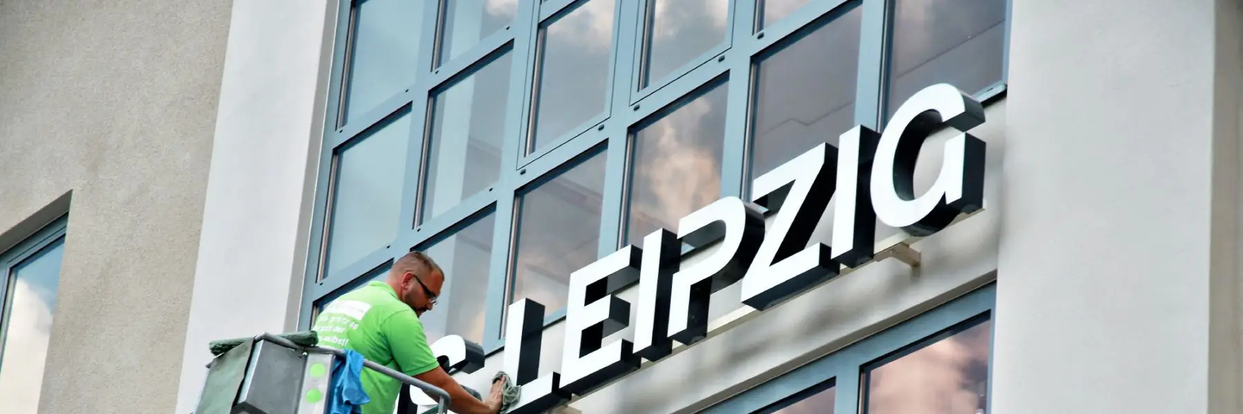 Mitarbeiter von DK-Gebäudereinigung reinigt die Fensterfront eines Gebäudes in Leipzig
